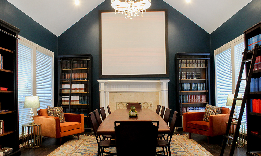 Image of the ministry interior study room with deep blue-green walls, standing bookcases a boardroom table and chairs flanked by comfortable orange colored upholestry and sitting pillows.